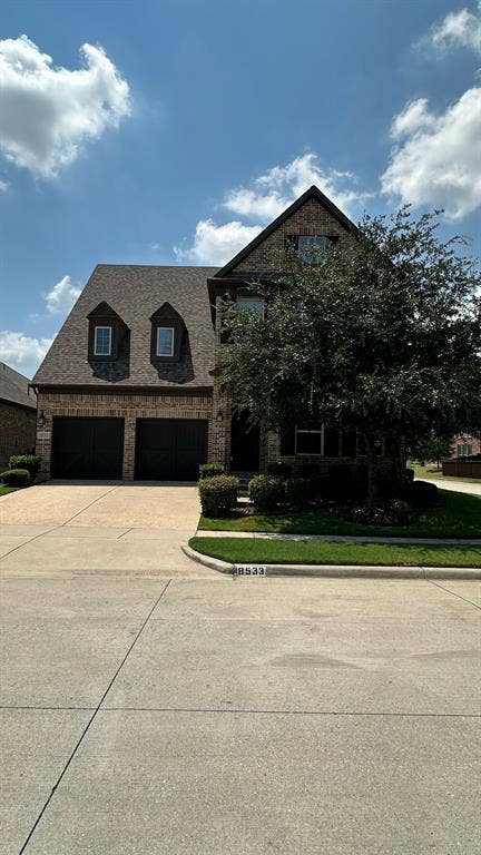 Brick exterior featuring a dark paneled entry door, covered porch, exterior lighting, and a metal handrail