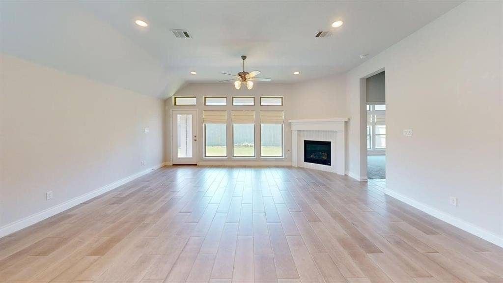 2401 Robin Way, Northlake, TX 76247 Vaulted ceiling with recessed lighting, wood-finish flooring, multiple windows with blinds, a fireplace with a mantel, and a ceiling fan