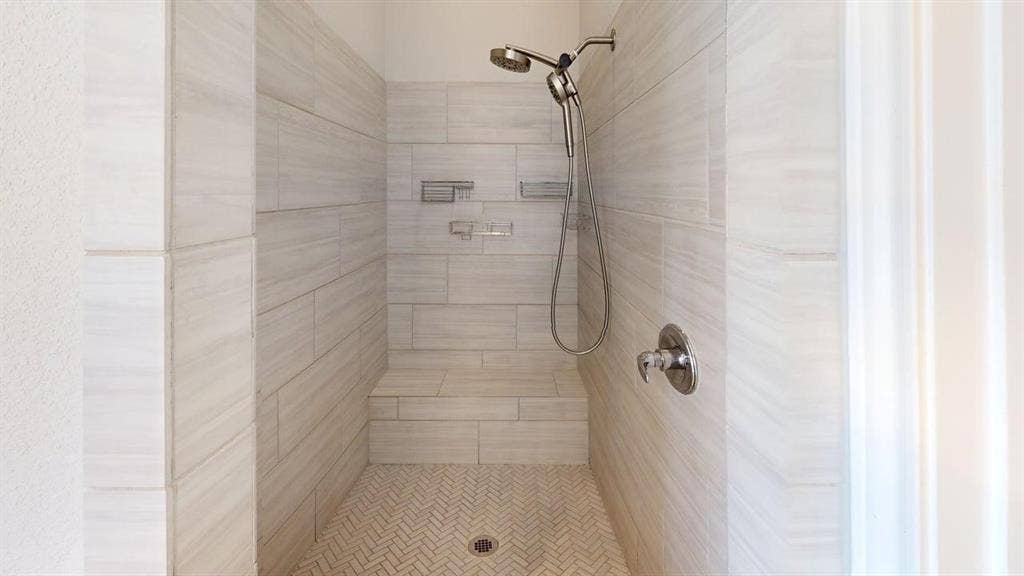 2401 Robin Way, Northlake, TX 76247 Walk-in shower with large-format tile walls, integrated shower bench, and a herringbone-patterned tile floor