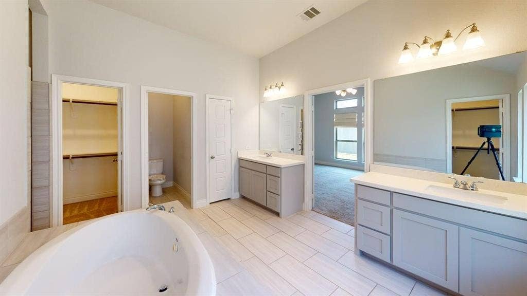 2401 Robin Way, Northlake, TX 76247 Soaking tub with tile surround, dual vanities with integrated sinks, wood-finish flooring, and vaulted ceiling
