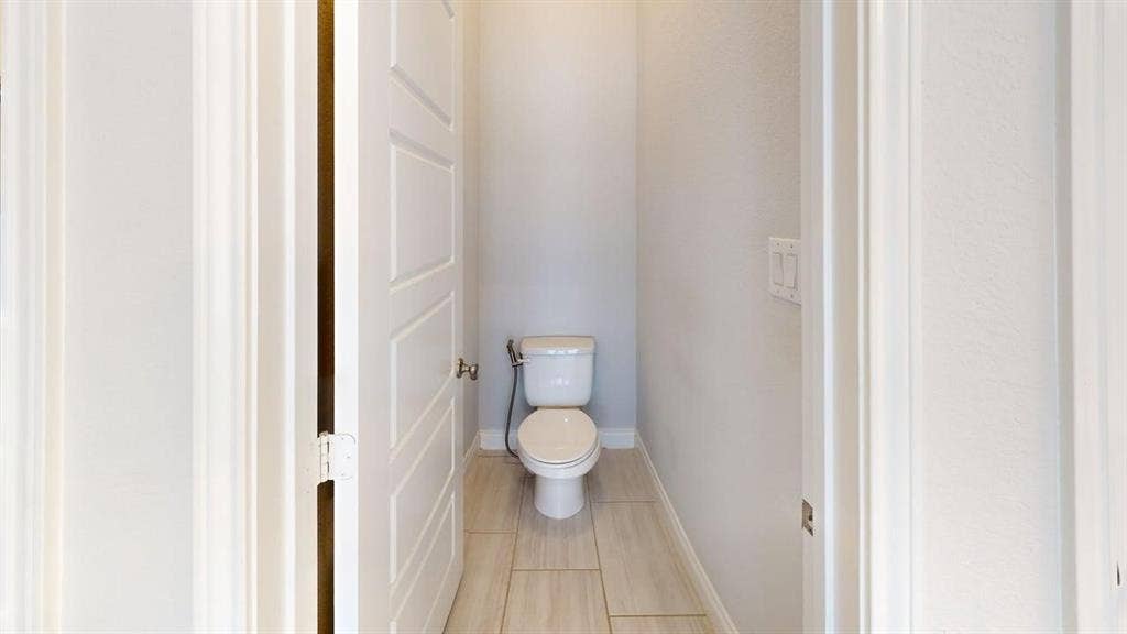 2401 Robin Way, Northlake, TX 76247 Recessed toilet in a dedicated alcove with light-toned rectangular floor tiles