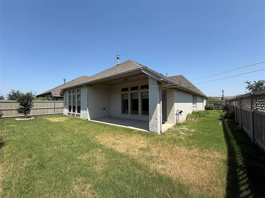2401 Robin Way, Northlake, TX 76247 Rear exterior with a covered concrete patio, brick facade, and a wood privacy fence