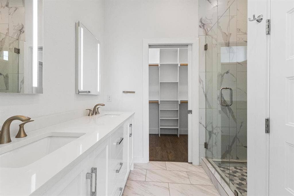 2450 N Garrett Avenue, #14, Dallas, TX 75206 Dual vanity with integrated sinks, white cabinetry, and wall-mounted illuminated mirrors