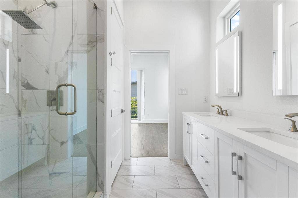 2450 N Garrett Avenue, #14, Dallas, TX 75206 Spacious bathroom featuring a glass-enclosed shower with a rain showerhead, a dual vanity with undermount sinks, and integrated mirror lighting