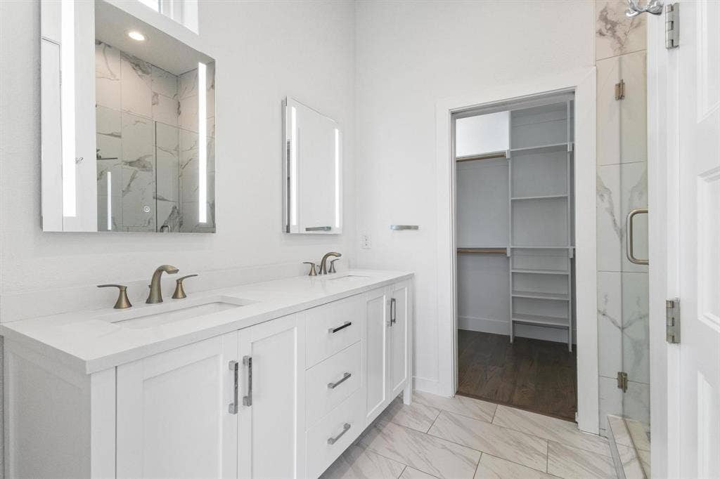 2450 N Garrett Avenue, #14, Dallas, TX 75206 Dual vanity with integrated sinks, illuminated mirrors, a glass-enclosed shower, and a custom closet system
