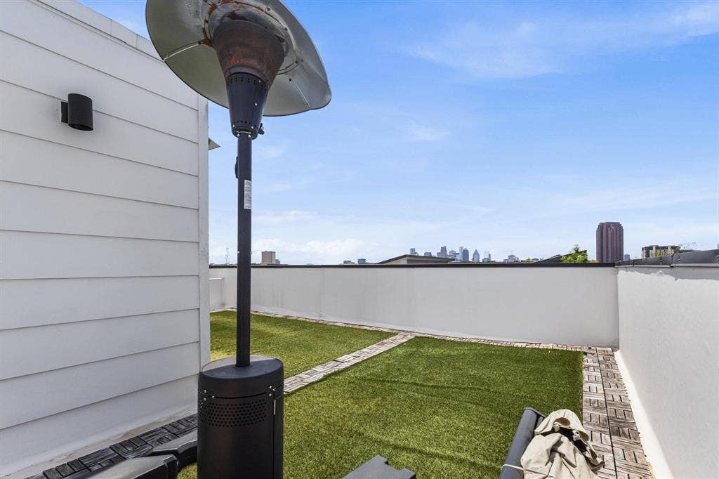 2450 N Garrett Avenue, #14, Dallas, TX 75206 Rooftop terrace featuring white siding, a permanent outdoor light fixture, artificial turf, and a city skyline in the distance
