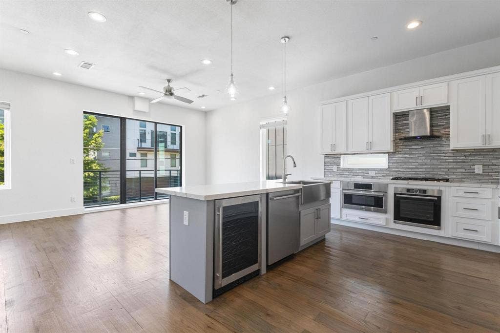 2450 N Garrett Avenue, #14, Dallas, TX 75206 Open-concept living space with wood-finish flooring, a contemporary kitchen, and a large sliding glass door opening to a balcony