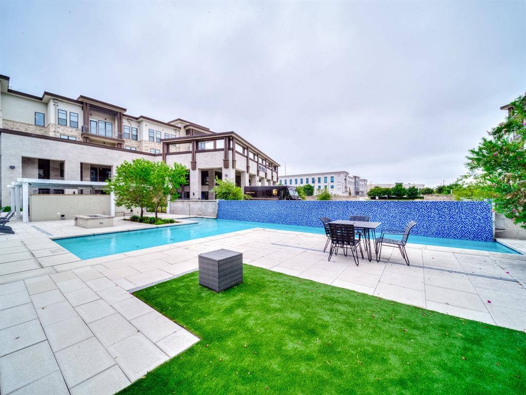 2700 Old Denton Road, #2212, Carrollton, TX 75007 Outdoor swimming pool with integrated spa, adjacent fire pit, artificial turf area, and surrounding paved patio