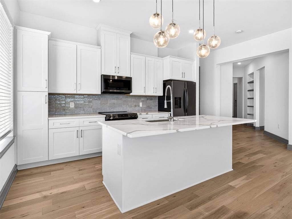 2700 Old Denton Road, #2212, Carrollton, TX 75007 White cabinetry, light wood-finish flooring, island with a white countertop, black appliances, and a gray tile backsplash