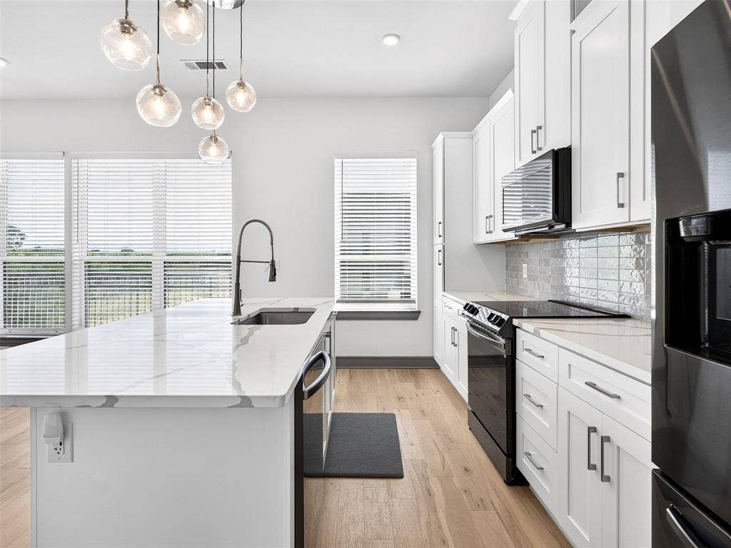 2700 Old Denton Road, #2212, Carrollton, TX 75007 Kitchen featuring a quartz-finish island with an undermount sink, pendant lighting, wood-finish flooring, white cabinetry, and a tile backsplash