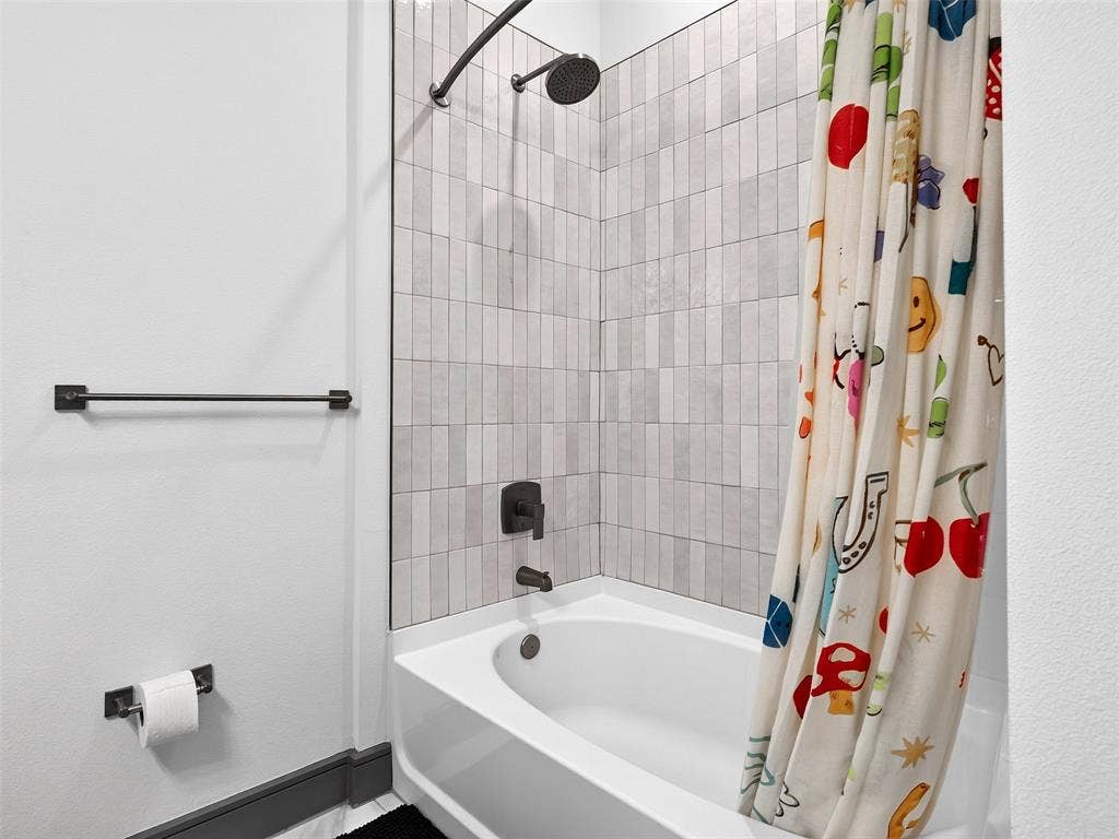 2700 Old Denton Road, #2212, Carrollton, TX 75007 Shower and tub combination with vertical tile surround, matte black shower head, and matte black faucet