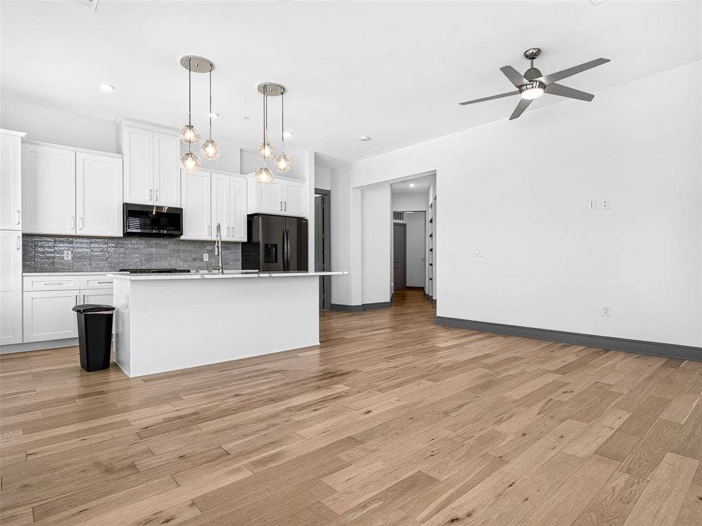 2700 Old Denton Road, #2212, Carrollton, TX 75007 White shaker cabinetry, dark tile backsplash, a kitchen island with seating, pendant lighting, and wood-finish flooring