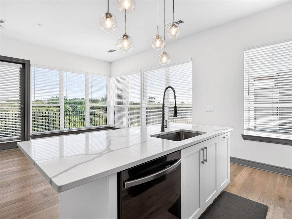 2700 Old Denton Road, #2212, Carrollton, TX 75007 Kitchen island featuring a single-basin sink, matte black faucet, and white countertop with veining