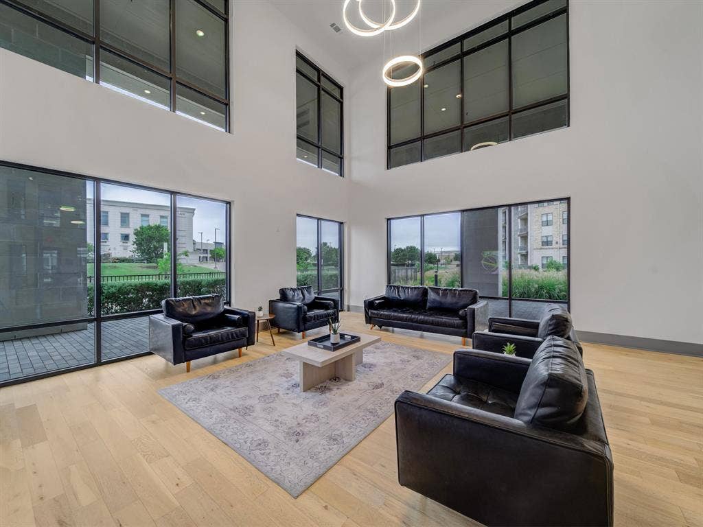 2700 Old Denton Road, #2212, Carrollton, TX 75007 Soaring ceilings with tall windows, natural wood-finish flooring, recessed lighting, and modern pendant light fixtures