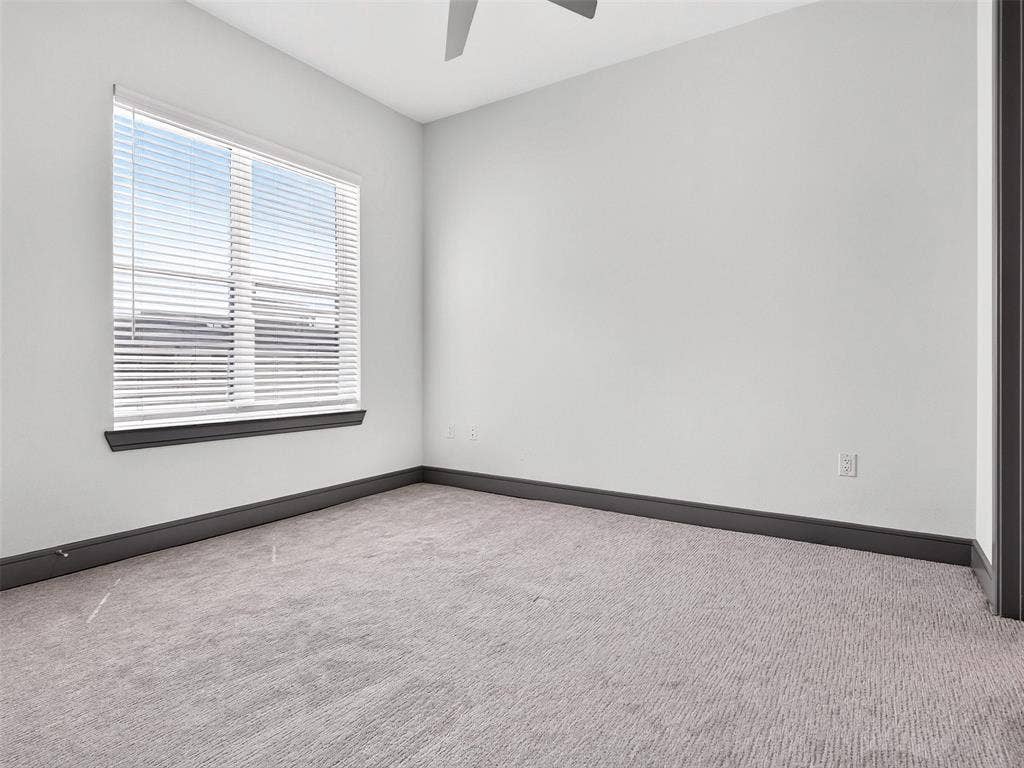 2700 Old Denton Road, #2212, Carrollton, TX 75007 Spacious room featuring light-toned walls, a single window with horizontal blinds, dark trim, and patterned carpeting