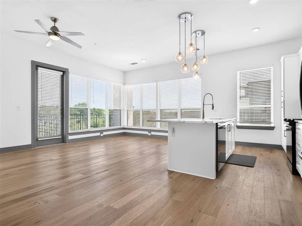 2700 Old Denton Road, #2212, Carrollton, TX 75007 Open-concept living area with wood-finish flooring, a contemporary kitchen island, and multiple windows