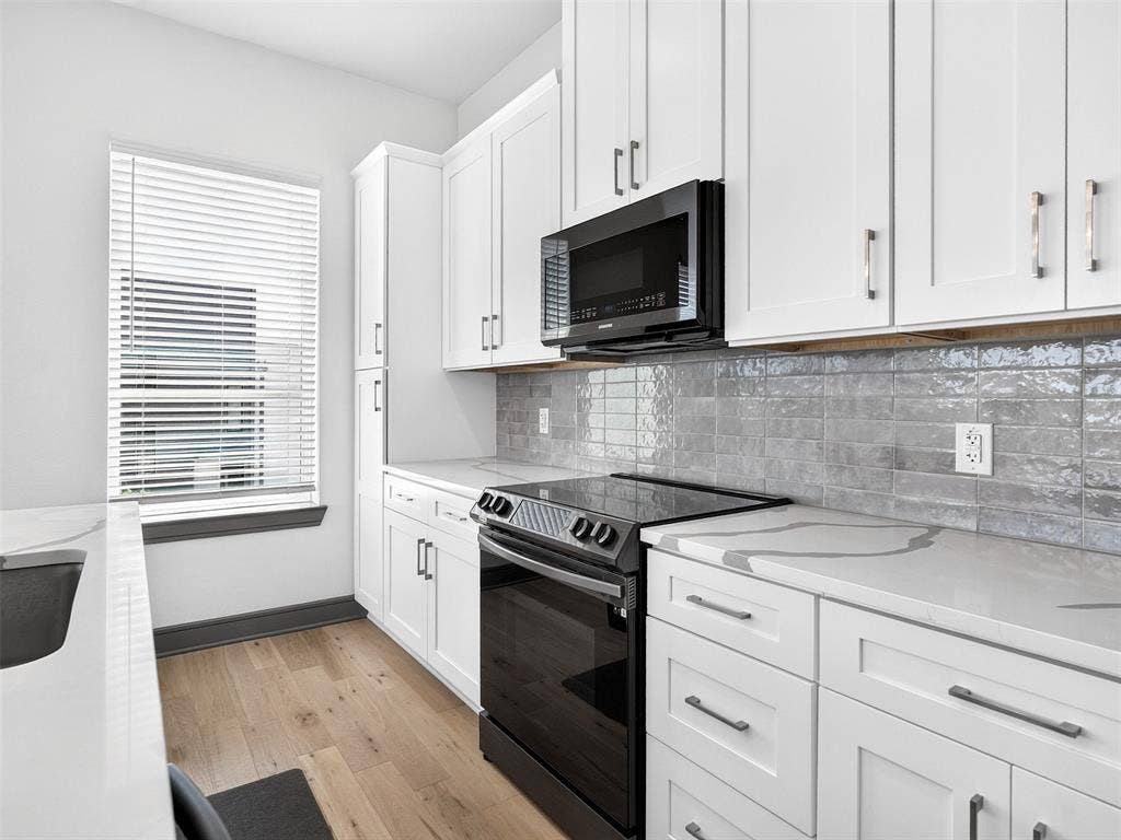 2700 Old Denton Road, #2212, Carrollton, TX 75007 White cabinetry, quartz countertops with gray veining, black built-in microwave, black electric range, and wood-finish flooring