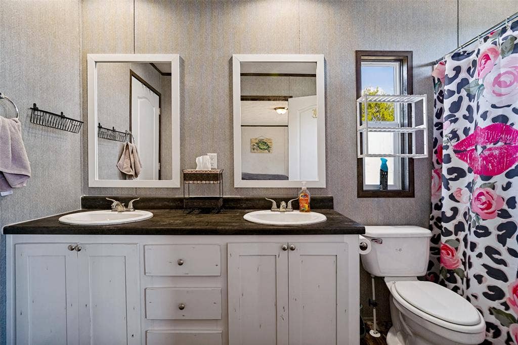 4415 Woodland Drive, Granbury, TX 76048 Dual vanity with white cabinetry, dark countertop, and integrated sinks