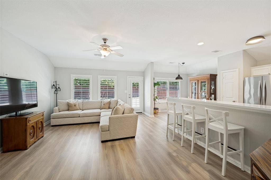 3707 Redwood Circle, Melissa, TX 75454 Expansive room featuring wood-finish flooring, a ceiling fan with light fixture, and multiple windows with plantation shutters