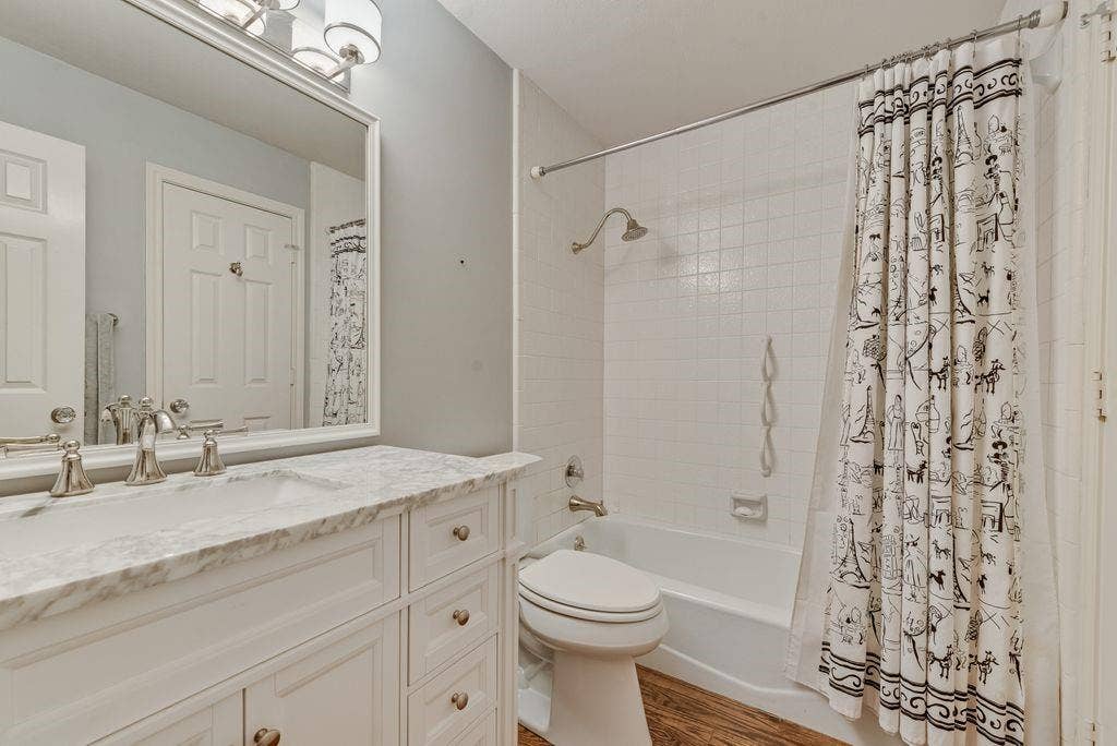2 Eastshore Road, Heath, TX 75032 Spa-inspired bathroom featuring a marble-topped vanity with dual sink configuration, polished nickel fixtures, and an expansive framed mirror