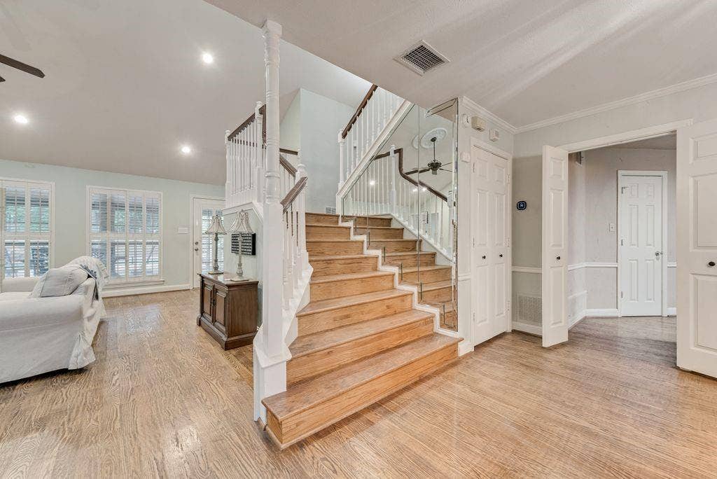 2 Eastshore Road, Heath, TX 75032 Hardwood flooring throughout, a grand staircase with wood newel posts and white balusters, recessed lighting, and multiple windows with plantation shutters