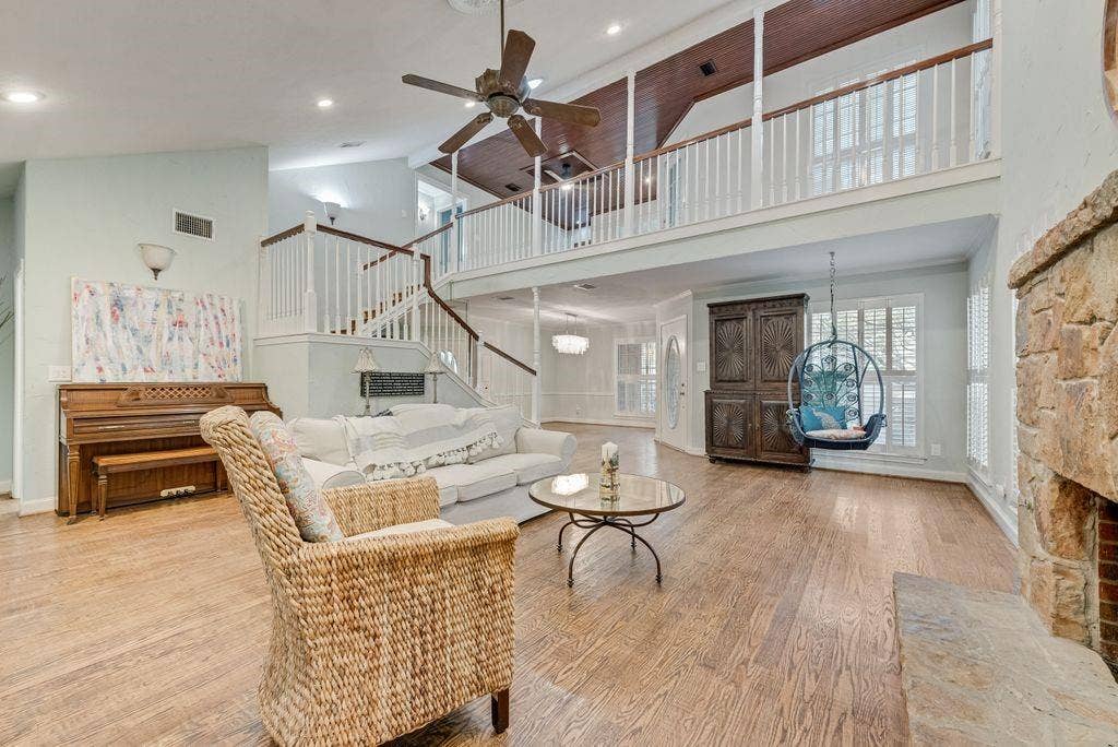 2 Eastshore Road, Heath, TX 75032 High ceilings with exposed wood beams, wood-finish flooring, two-story stone fireplace, white baluster staircase, and abundant natural light