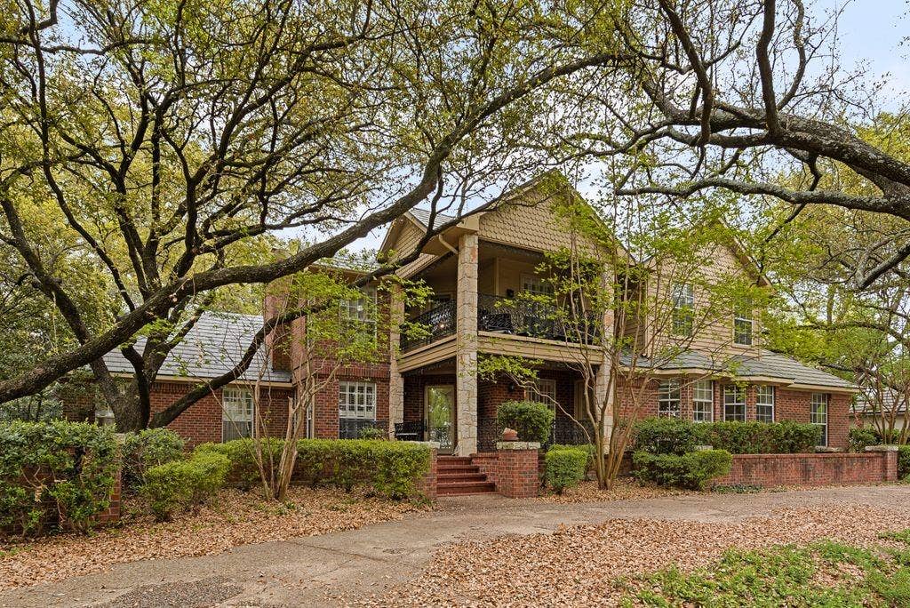 2 Eastshore Road, Heath, TX 75032 Brick exterior with a stone column porch, an upper-level balcony, dormer windows, and a multi-level roofline