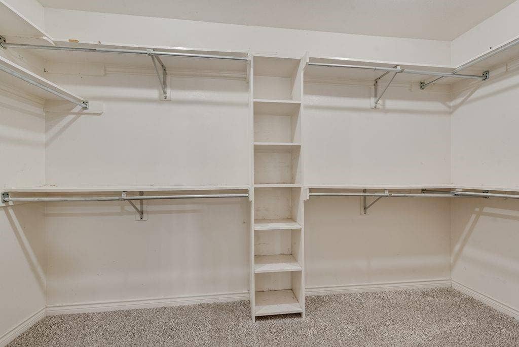 2 Eastshore Road, Heath, TX 75032 Custom closet system featuring built-in shelving, hanging rods, and light-tone carpeting