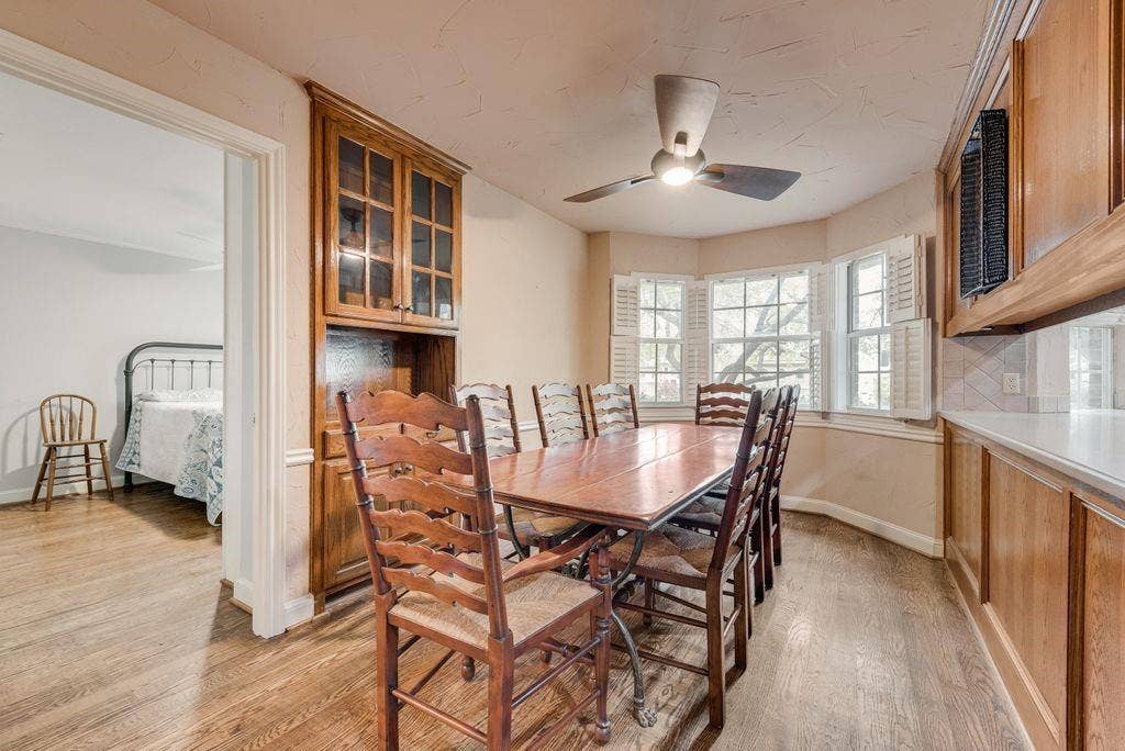 2 Eastshore Road, Heath, TX 75032 Wood-finish flooring throughout, built-in cabinetry with glass display, bay window with plantation shutters, ceiling fan with integrated lighting, and a neutral color palette