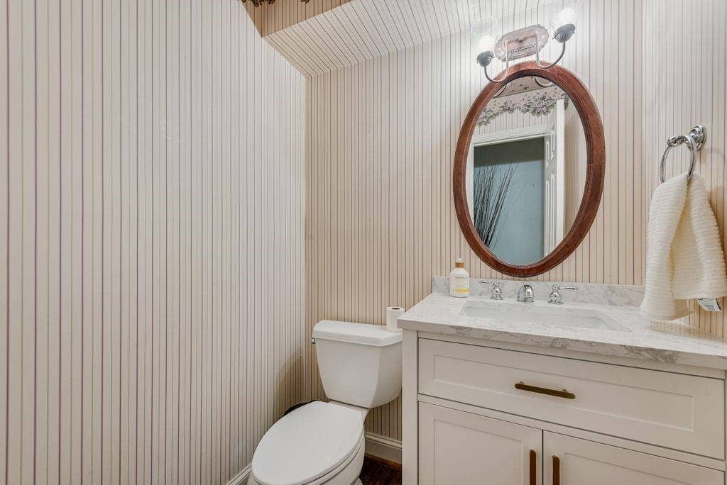 2 Eastshore Road, Heath, TX 75032 White vanity with a stone countertop, an oval wood-framed mirror, and a chrome towel ring