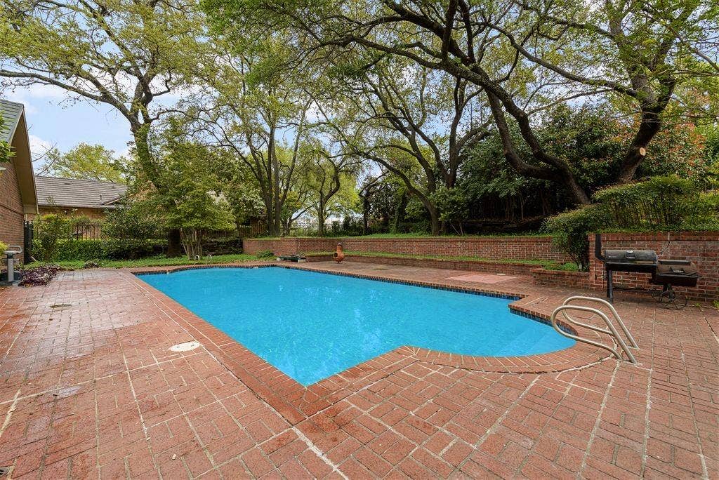 2 Eastshore Road, Heath, TX 75032 Rectangular swimming pool with integrated steps, surrounded by brick paver decking and a brick retaining wall