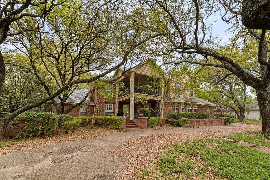 2 Eastshore Road, Heath, TX 75032 Brick exterior with a covered front balcony, mature trees, and an expansive driveway
