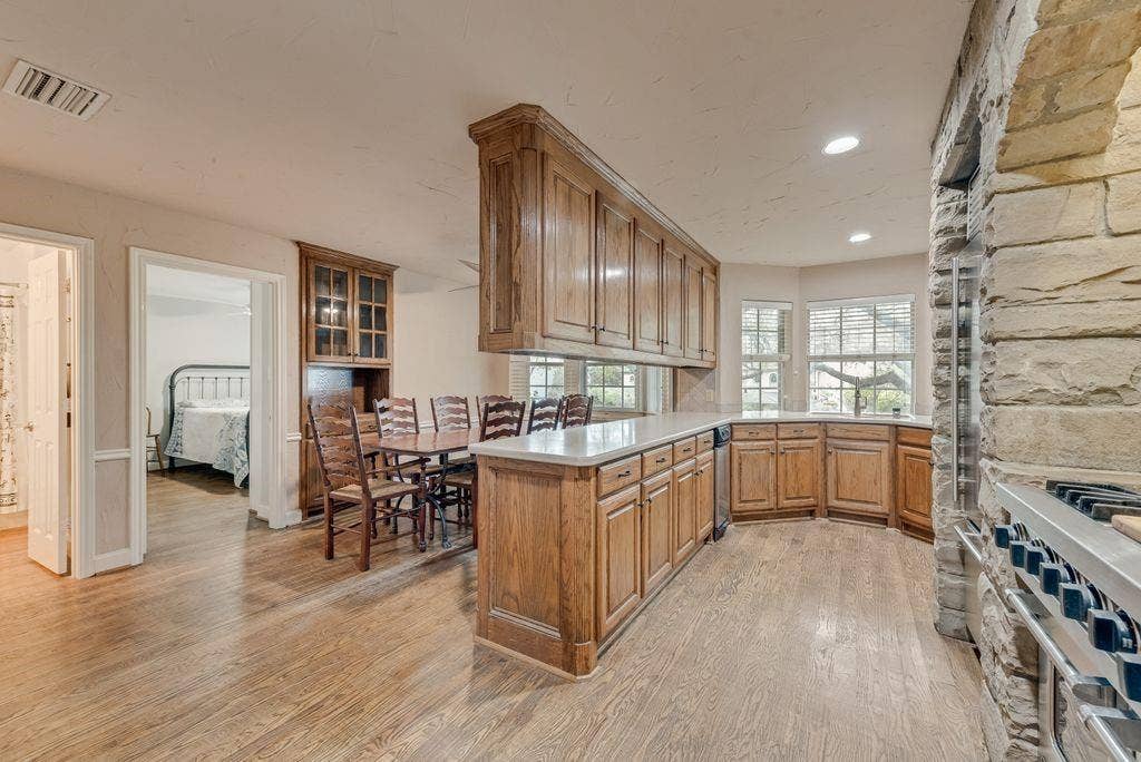 2 Eastshore Road, Heath, TX 75032 Kitchen featuring wood-finish flooring, custom wood cabinetry, and stone architectural details