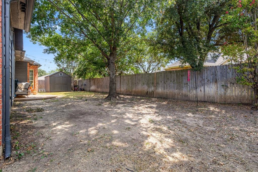 5413 Compassion Drive, Midlothian, TX 76065 Expansive backyard featuring mature trees, a privacy fence, a concrete patio, and a storage shed