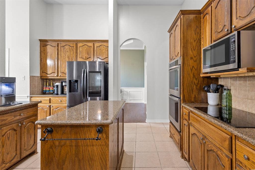 5413 Compassion Drive, Midlothian, TX 76065 Kitchen featuring wood cabinetry, stainless steel appliances, granite countertops, and tile flooring