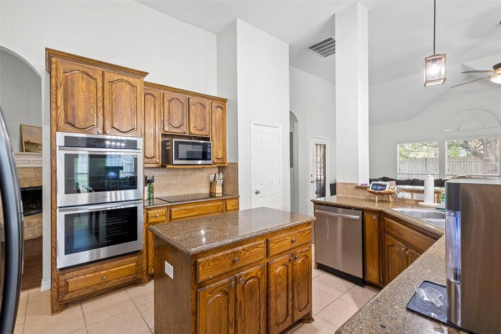 5413 Compassion Drive, Midlothian, TX 76065 Kitchen featuring wood cabinetry, stainless steel double wall ovens, a central island, and a tile backsplash