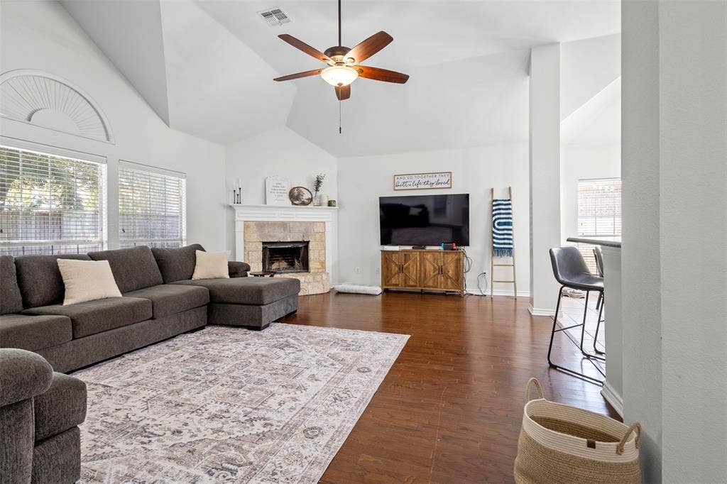 5413 Compassion Drive, Midlothian, TX 76065 Vaulted ceiling, wood-finish flooring, stone-surround fireplace, ceiling fan, and large windows with arched transom