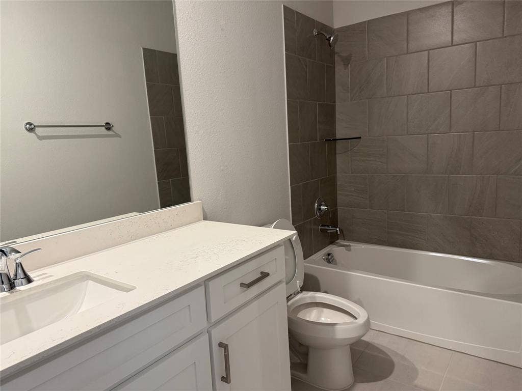 Bathroom featuring a vanity with an integrated sink, a built-in bathtub with a tile surround, and a chrome faucet and shower head