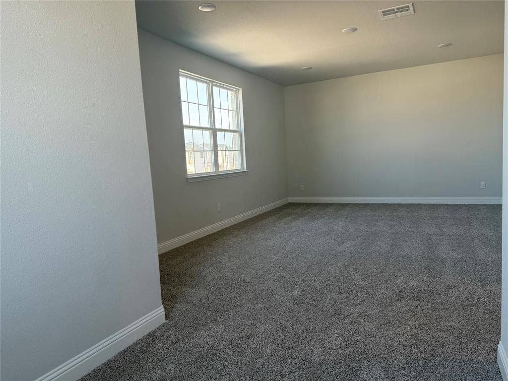 Recessed lighting, neutral wall tones, large window with grid pattern, white trim, and gray carpet