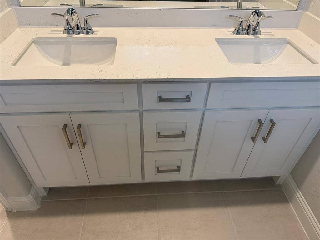Dual vanity with integrated sinks and chrome fixtures, white cabinetry, and a light-toned countertop