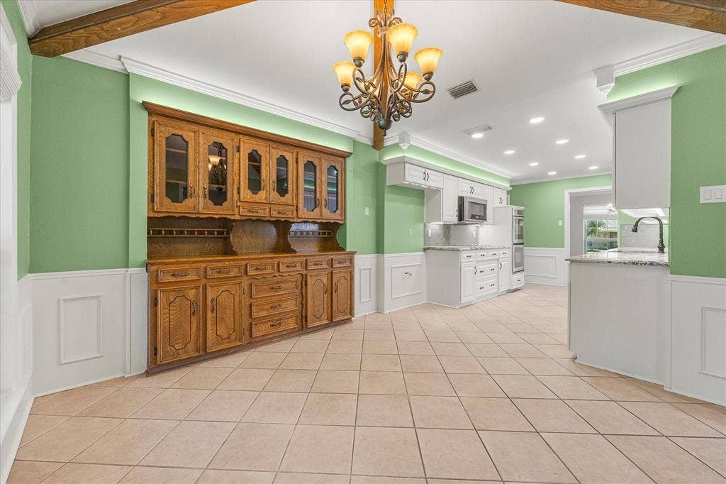 4001 Keele Drive, Garland, TX 75041 Breakfast and kitchen area featuring a built-in cabinet, decorative lighting, and neutral ceramic tile. While sitting at your breakfast table, you will have a view of the spacious backyard.