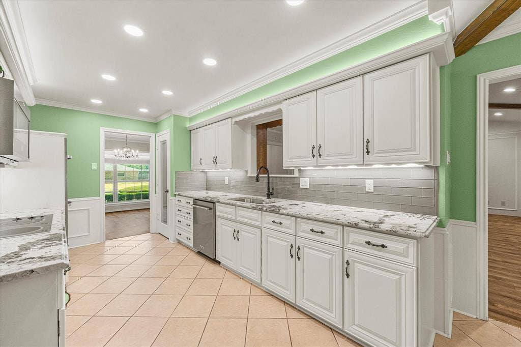 4001 Keele Drive, Garland, TX 75041 Updated kitchen with granite countertops, undercounter lighting, above-cabinet lighting, updated and abundant cabinetry, and stylish tile backsplash.
