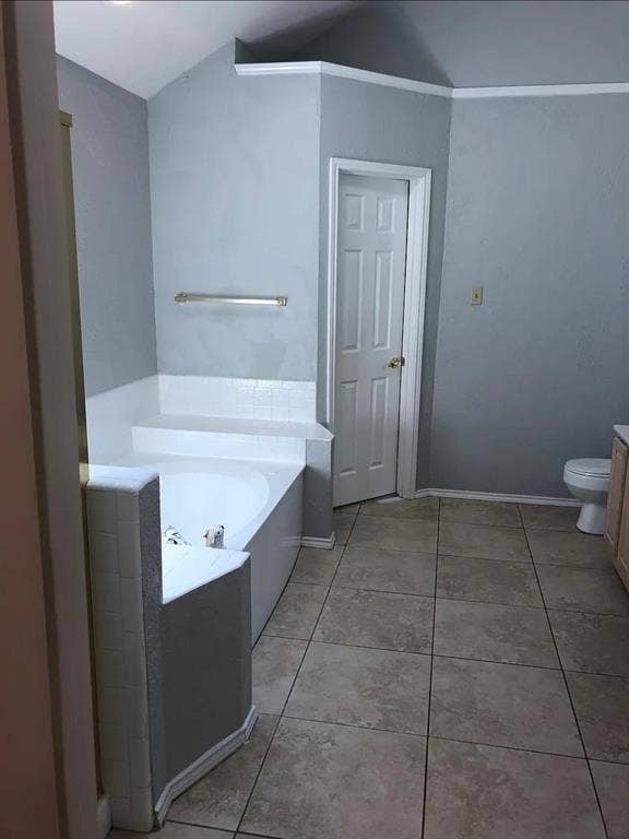 550 Village Green Drive, Coppell, TX 75019 Built-in corner tub with tiled surround, light-toned floor tile, and white paneled door