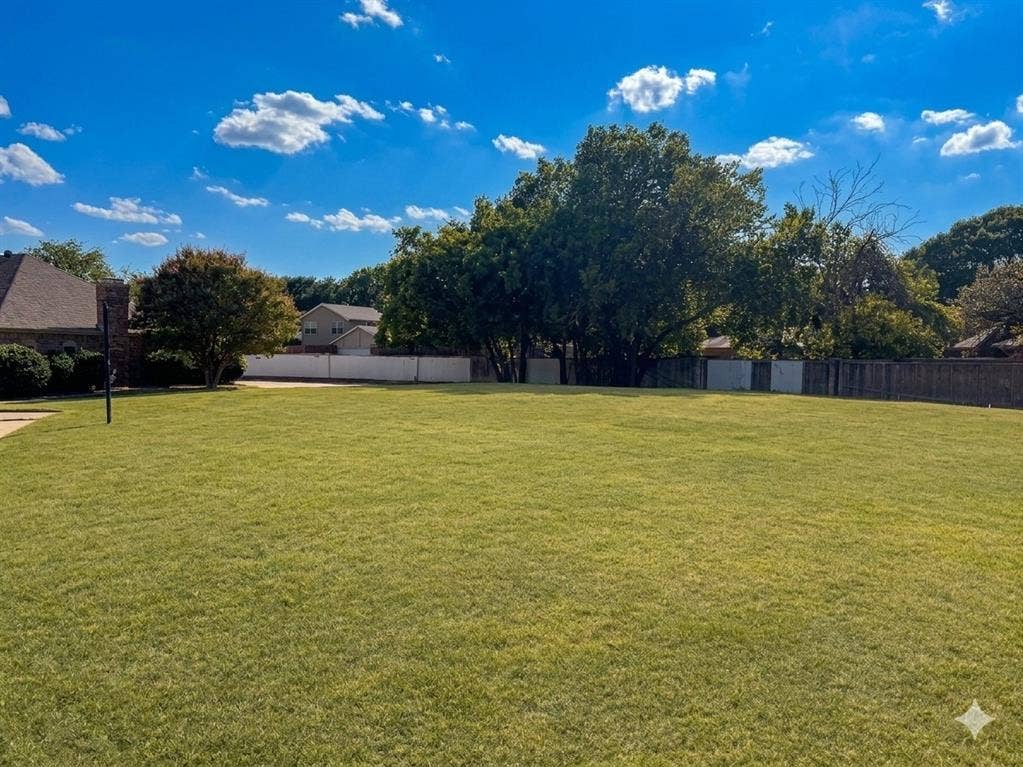 Expansive green lawn with established trees and a combination privacy fence