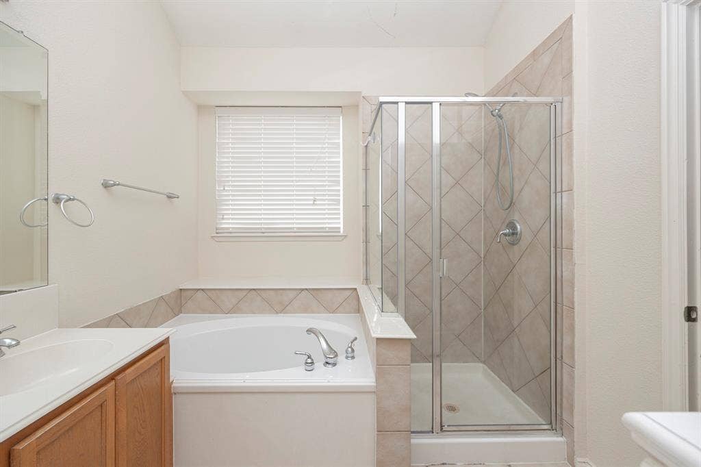 5728 Calloway Drive, McKinney, TX 75070 Shower with glass enclosure and tiled surround, soaking tub, vanity with sink, window with blinds