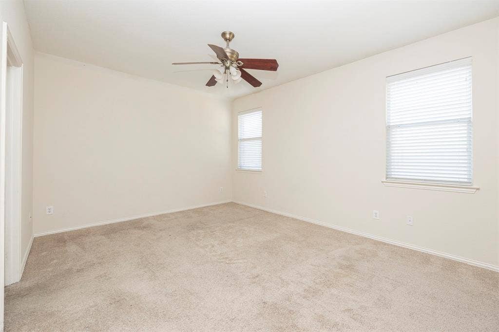5728 Calloway Drive, McKinney, TX 75070 Neutral carpeting, two windows with blinds, and a ceiling fan with light fixture