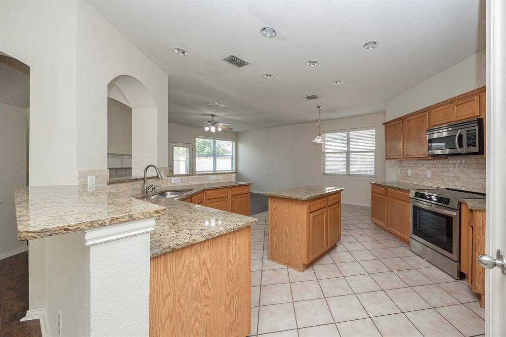5728 Calloway Drive, McKinney, TX 75070 Kitchen featuring tile flooring, wood cabinetry, stone countertops, stainless steel appliances, and recessed lighting