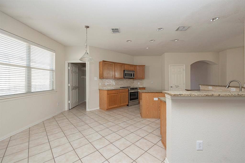 5728 Calloway Drive, McKinney, TX 75070 Kitchen featuring wood cabinetry, stainless steel appliances, granite countertops, and tiled flooring