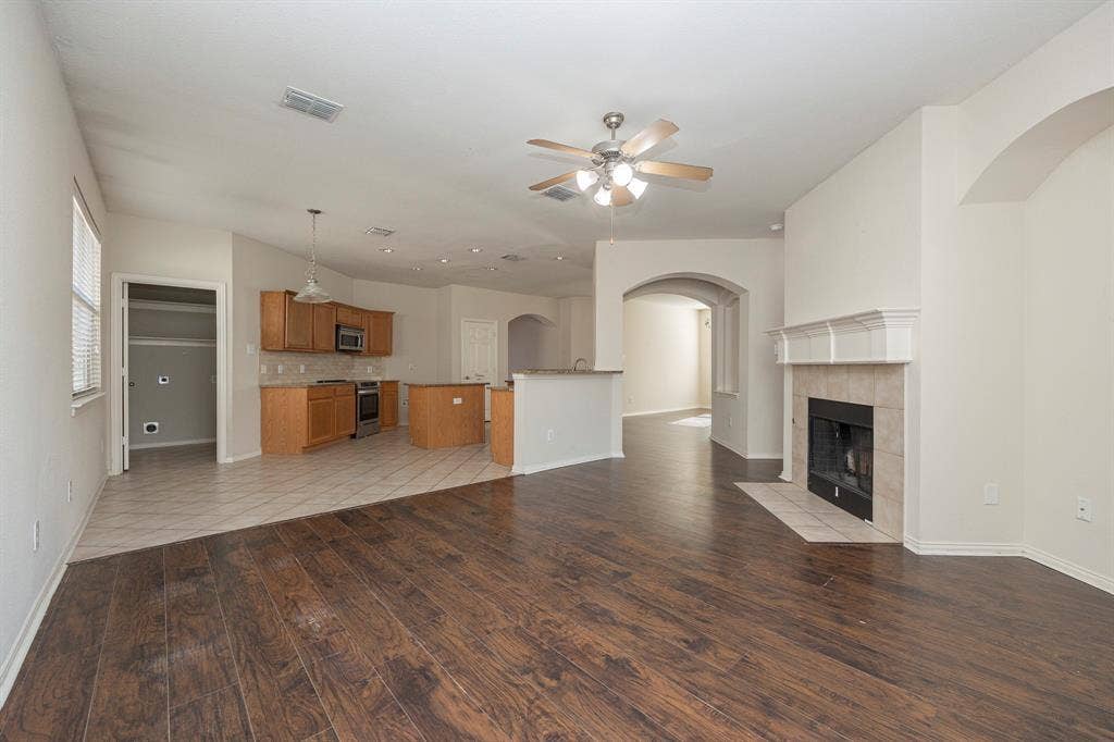 5728 Calloway Drive, McKinney, TX 75070 Living area with dark wood-finish flooring, a tile fireplace, and an arched entry
