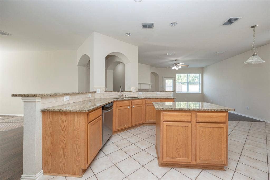 5728 Calloway Drive, McKinney, TX 75070 Kitchen featuring a central island, light wood-finish cabinetry, light-toned countertops, and a stainless steel dishwasher